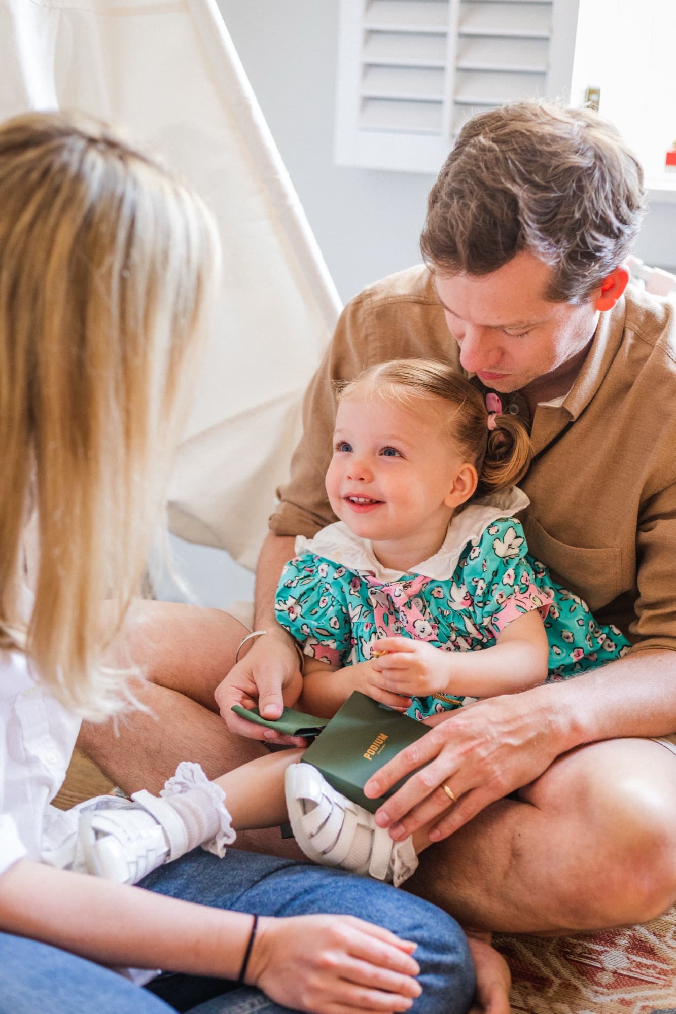 A father kissing his smiling toddler as she opens a small green box